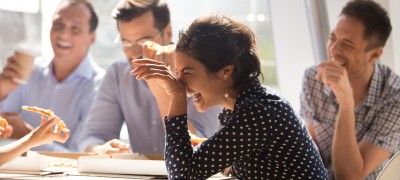 People sitting around a table laughing and eating pizza.