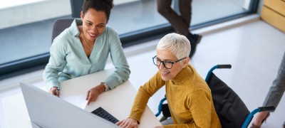 Two people sitting in front of a laptop in a office.