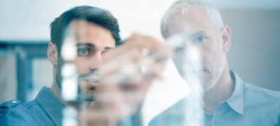 Two individuals examining a transparent screen.
